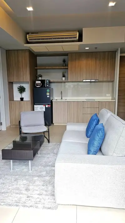 Modern living room with open kitchen, stylish furniture, and cozy ambiance.