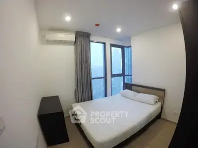 Modern bedroom with large windows and minimalist decor in a high-rise apartment.