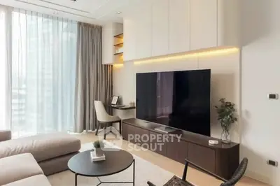 Modern living room with large TV, stylish furniture, and natural light