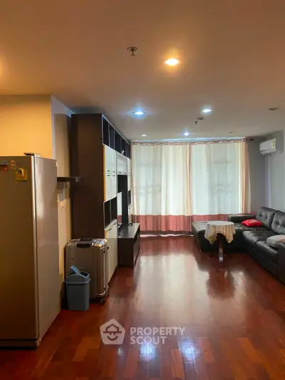 Spacious living room with wooden flooring and modern furniture in a cozy apartment.