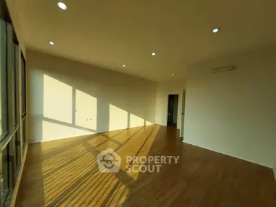 Spacious sunlit living room with wooden flooring and modern lighting