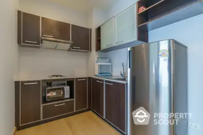 Modern kitchen with sleek cabinets and stainless steel fridge in a compact layout.