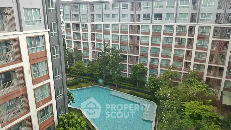 Modern apartment complex with lush greenery and a large swimming pool view.