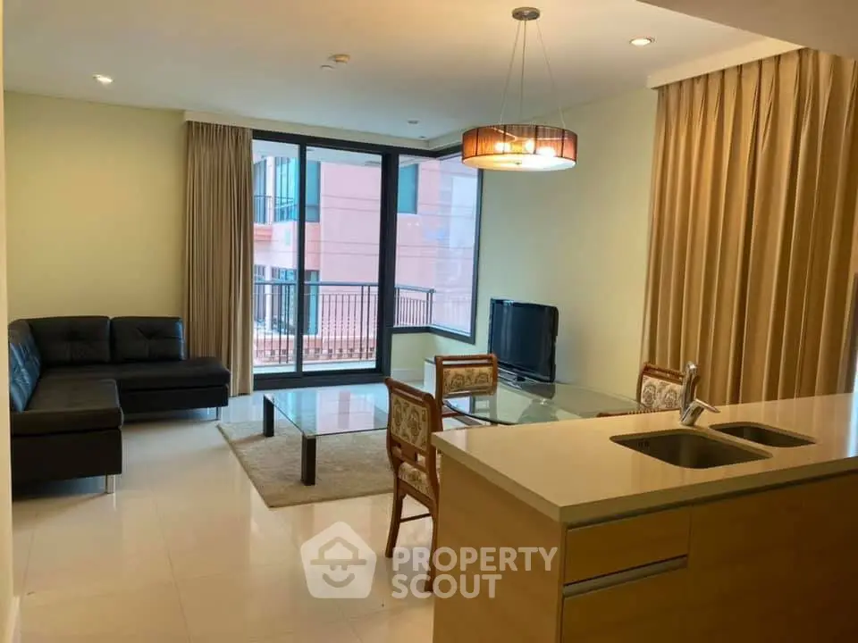 Modern living room with open kitchen, sleek furniture, and large windows for natural light.