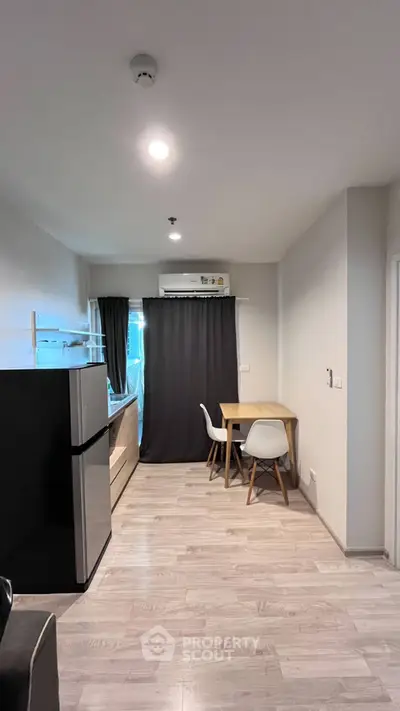 Modern apartment interior with sleek kitchen and dining area, featuring stylish furniture and bright lighting.