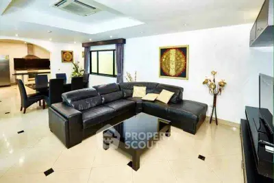 Spacious modern living room with sleek black leather sofa and elegant dining area.