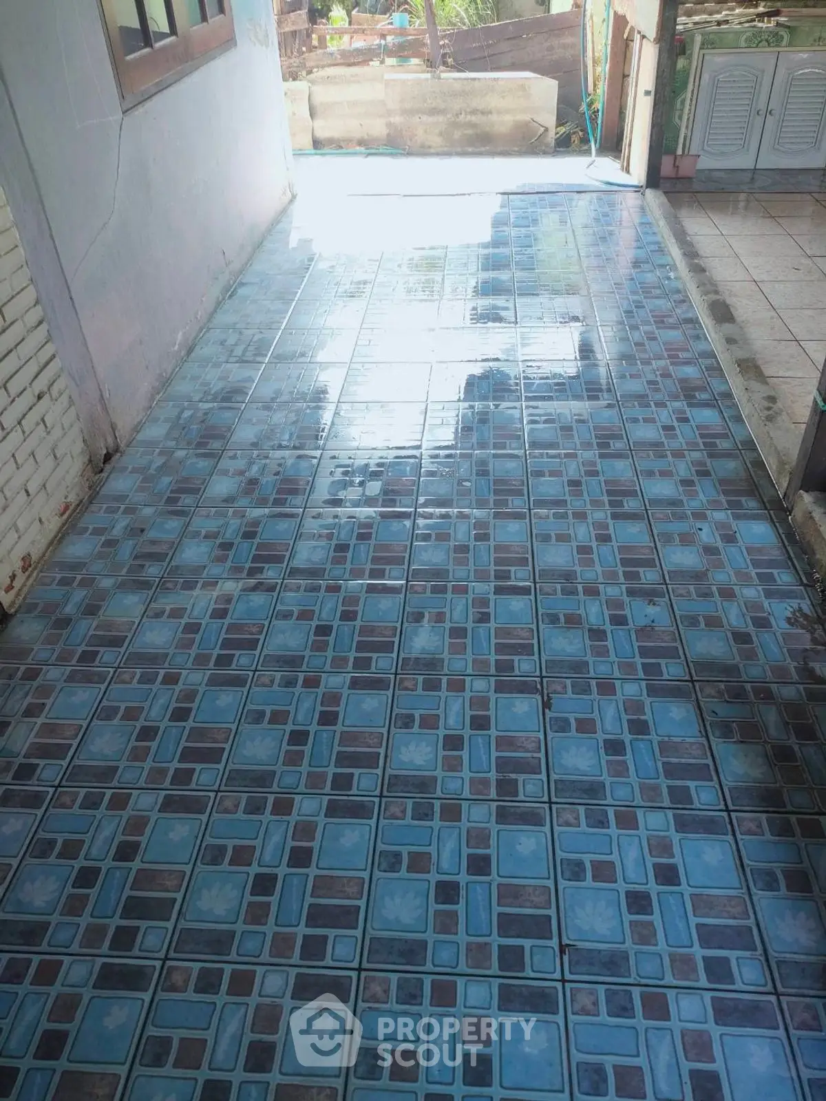 Spacious tiled corridor with blue patterned flooring and natural light.