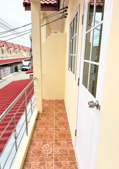 Charming balcony with tiled flooring and white door, offering a cozy outdoor space in a residential area.