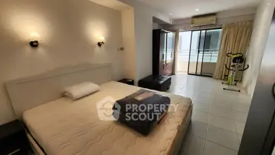 Spacious bedroom with balcony access and exercise equipment in modern apartment.