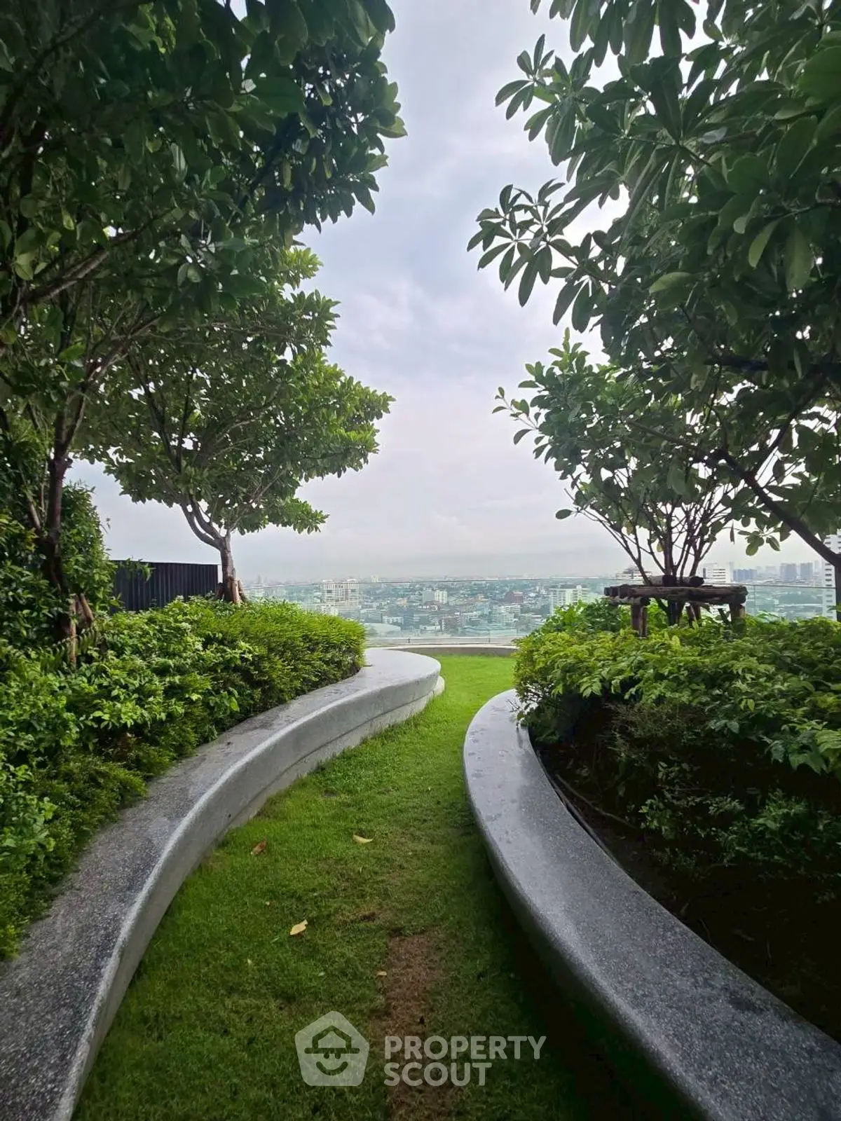Serene rooftop garden with lush greenery and stunning city view.