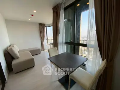 Modern living room with large windows and city view, featuring a cozy sofa and dining table.