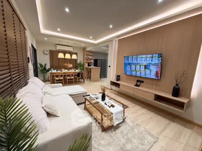 Modern living room with open kitchen, featuring stylish decor and ambient lighting.
