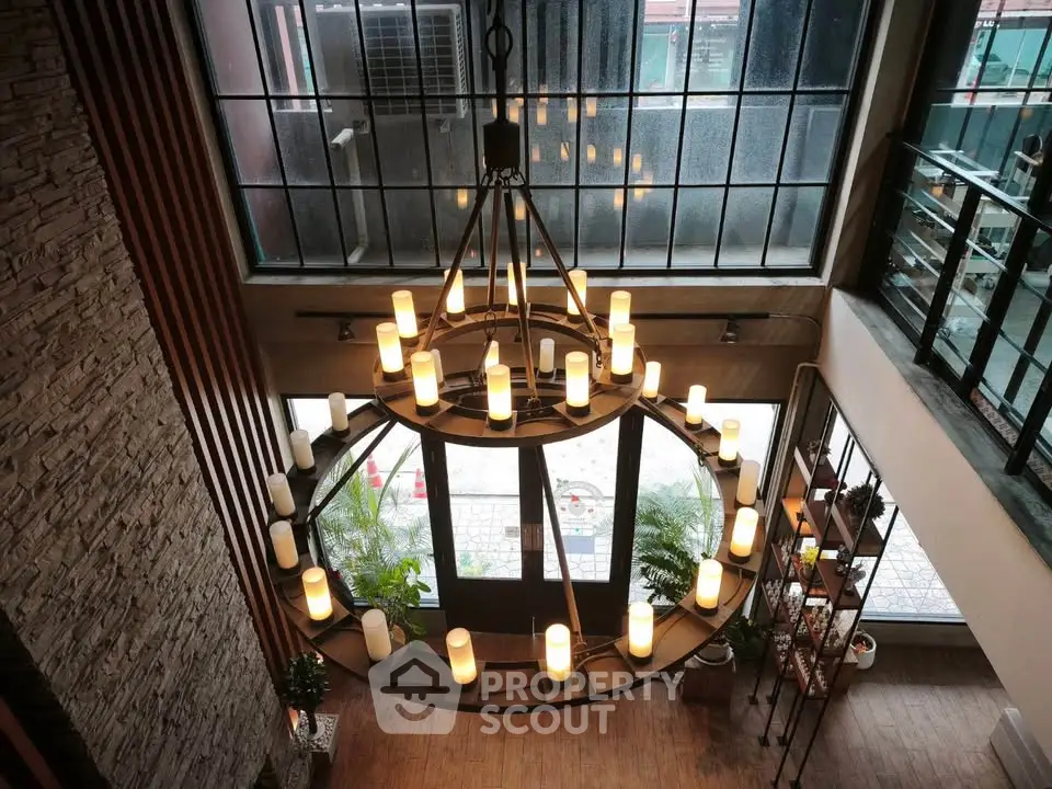 Stunning industrial-style entrance with large chandelier and floor-to-ceiling windows.