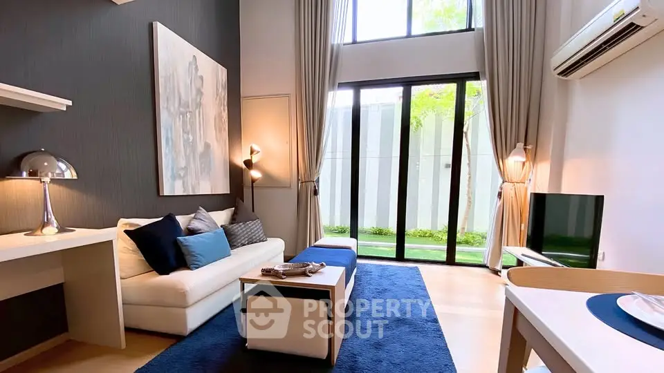 Modern living room with high ceilings, large windows, and stylish decor in a contemporary apartment.