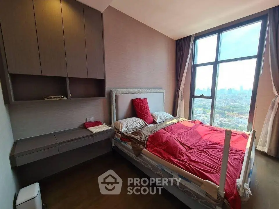 Modern bedroom with large window offering stunning city view, featuring stylish furniture and cozy bedding.