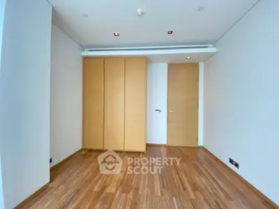 Spacious empty room with wooden flooring and modern closet in a luxury apartment.