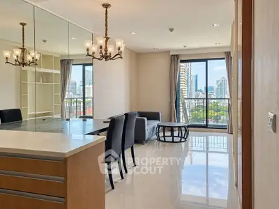 Spacious modern living room with city view, elegant chandelier, and sleek furniture in a high-rise apartment.