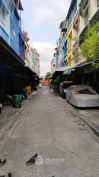 Charming urban alleyway with colorful buildings and parked vehicles, perfect for city living enthusiasts.