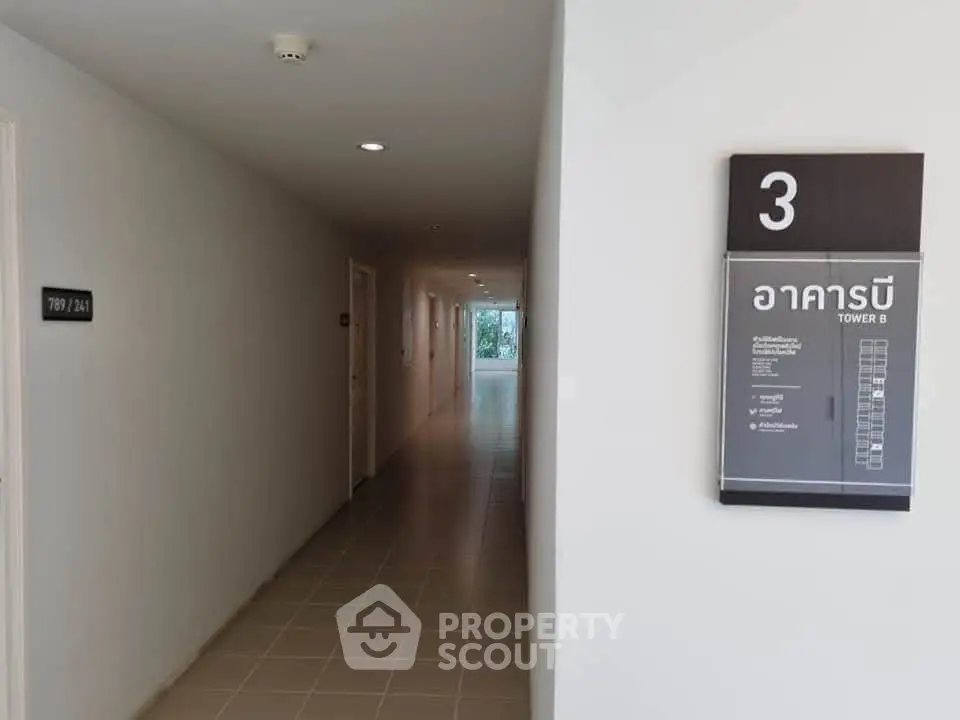 Modern apartment hallway with room numbers and tower sign, sleek design.
