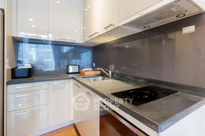 Modern kitchen with sleek cabinets and electric stove in contemporary apartment.
