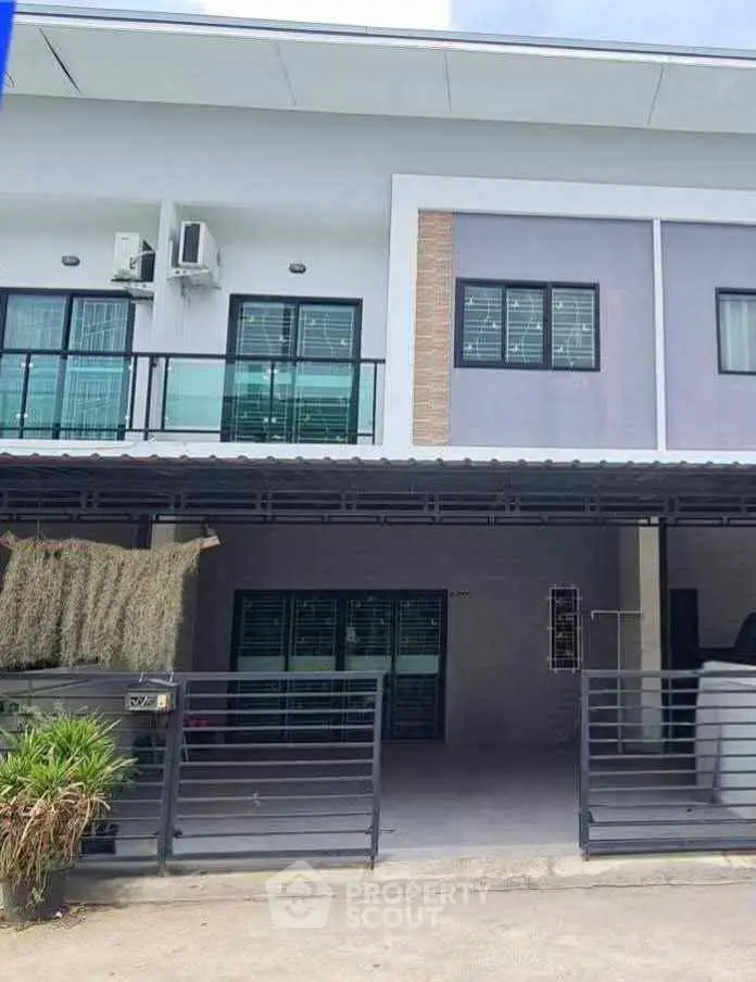 Modern two-story house with balcony and gated entrance, featuring sleek design and contemporary architecture.
