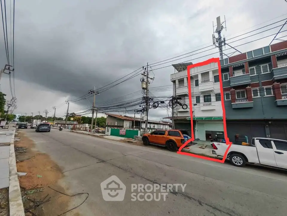 Street view of a commercial building with parking and cloudy sky