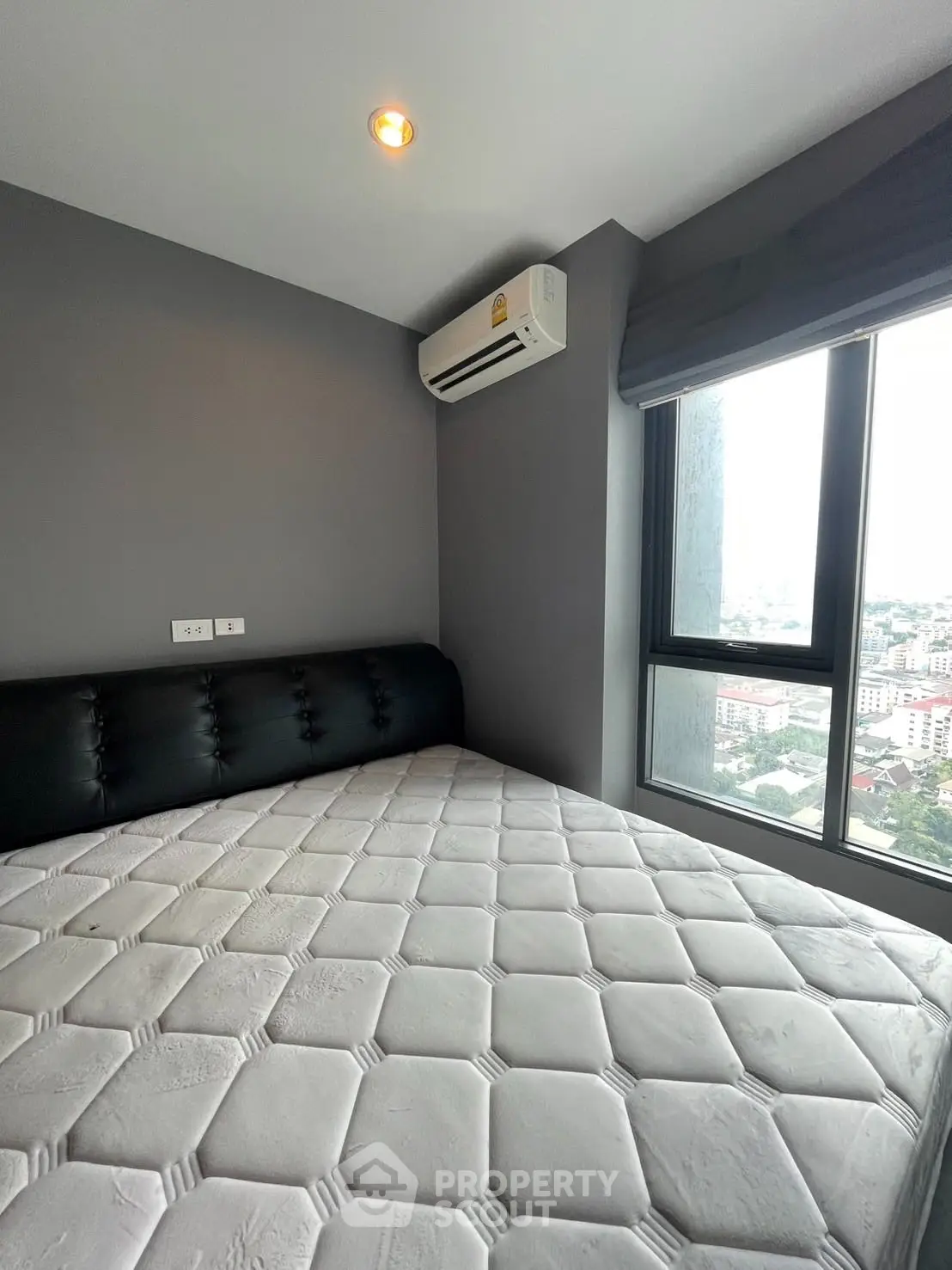 Modern bedroom with city view and air conditioning in high-rise apartment
