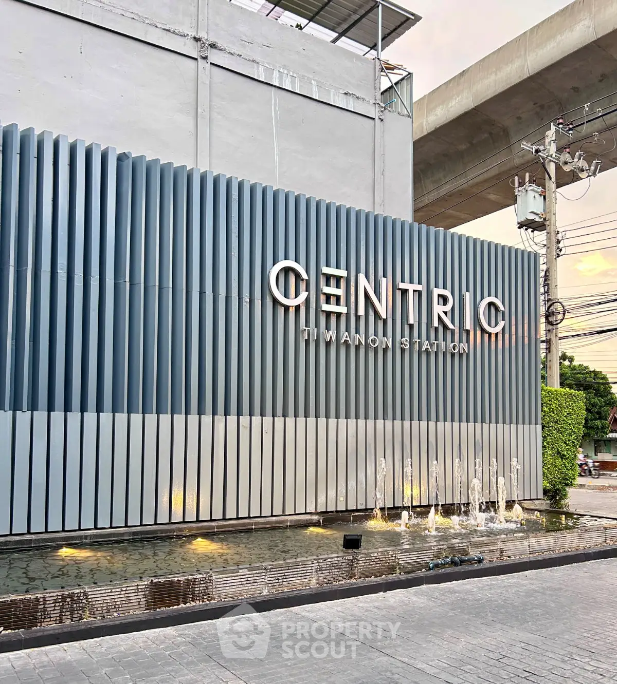 Modern building entrance with sleek design and water feature at Centric Tiwanon Station.