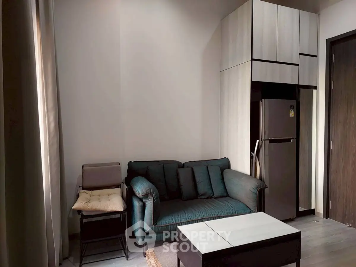 Cozy living room with modern sofa and compact kitchen area in stylish apartment.