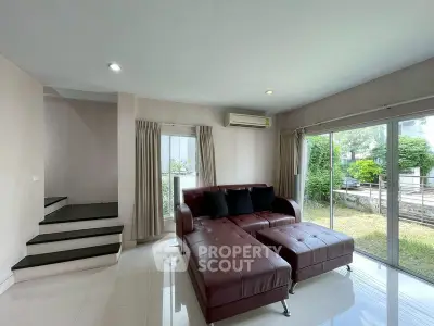 Spacious living room with modern sofa and garden view, perfect for relaxation and entertaining.