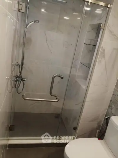 Modern bathroom with glass shower enclosure and marble walls