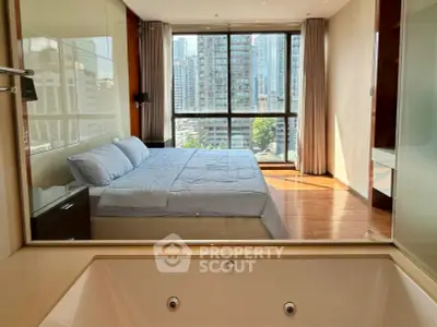 Luxurious bedroom with city view and ensuite bathtub in modern high-rise apartment.