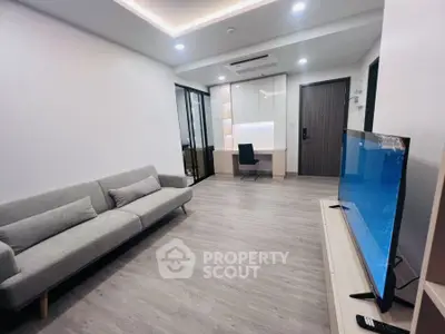 Modern living room with sleek design and spacious layout featuring a large TV and comfortable sofa.