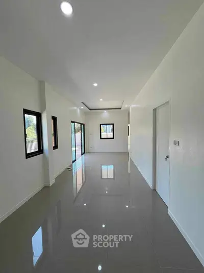 Spacious modern living room with glossy tiled floors and large windows for natural light.