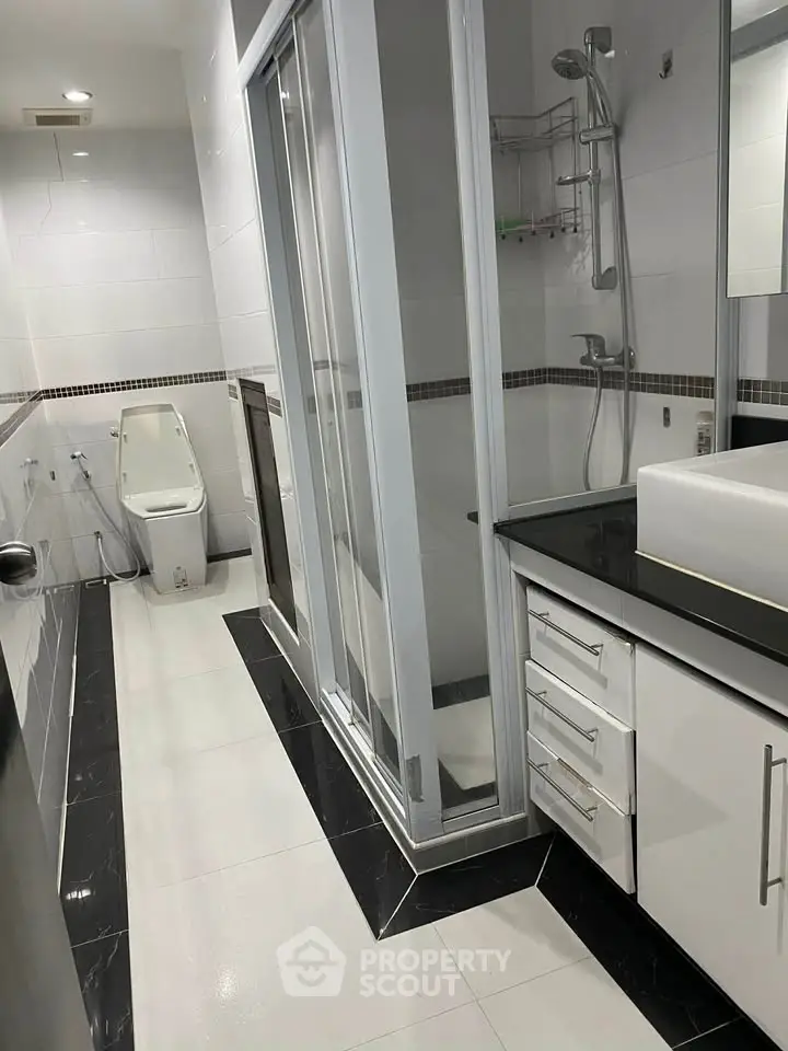 Modern bathroom with sleek design, featuring a glass shower enclosure and contemporary fixtures.