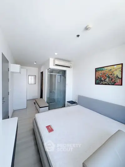 Modern bedroom with glass shower, air conditioning, and stylish decor in a contemporary apartment.