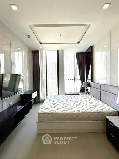 Luxurious modern bedroom with large windows and sleek furnishings in high-rise apartment.