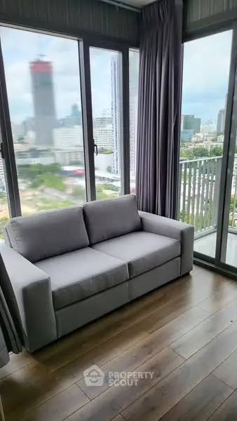 Modern living room with panoramic city view and cozy gray sofa.