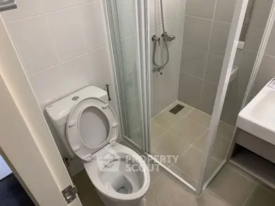 Modern bathroom with shower and toilet in a compact layout.
