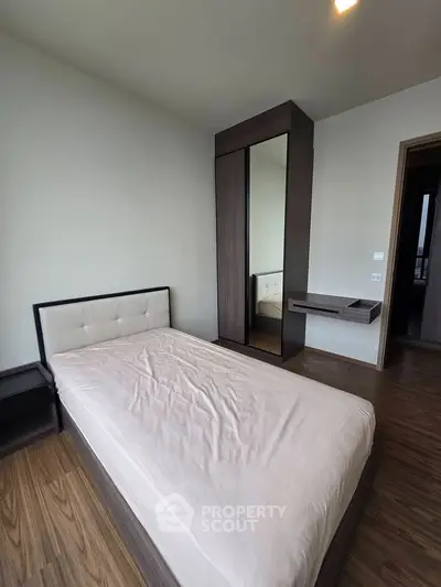Modern minimalist bedroom with single bed and sleek wardrobe in a stylish apartment.