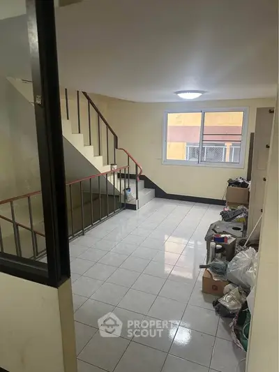 Spacious interior stairwell with tiled flooring and large window, ideal for natural light.