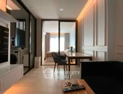 Modern open-plan living room with sleek furniture and glass partition to bedroom