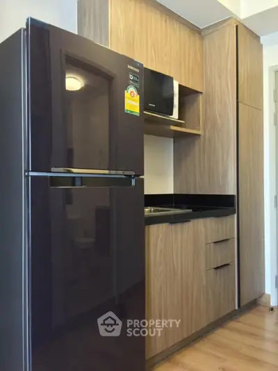 Modern kitchen with sleek black fridge and wooden cabinetry