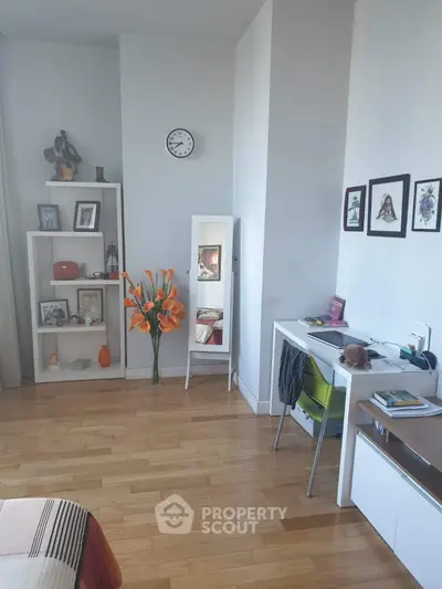 Charming bedroom with wooden floors, modern decor, and a cozy study nook.