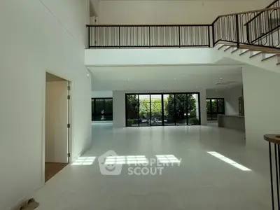 Spacious modern living room with high ceilings and large windows overlooking a garden.