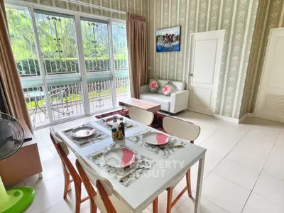 Charming living room with elegant wallpaper and large windows offering lush garden views.