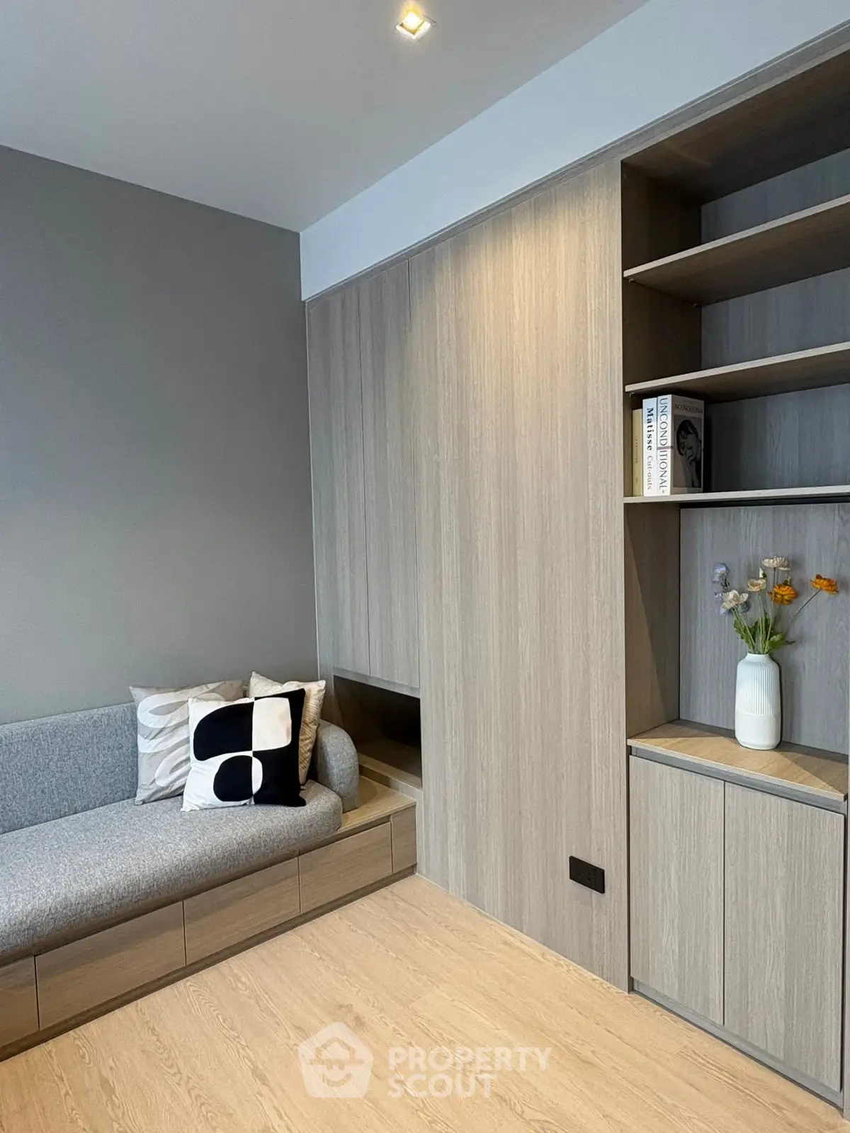 Modern living room with sleek wooden cabinetry and cozy gray sofa.