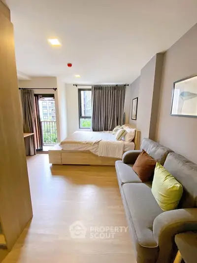 Modern studio apartment with cozy living area and large windows for natural light.