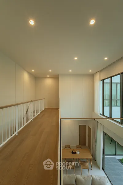 Modern duplex interior with open living area and dining space, featuring large windows and wooden flooring.