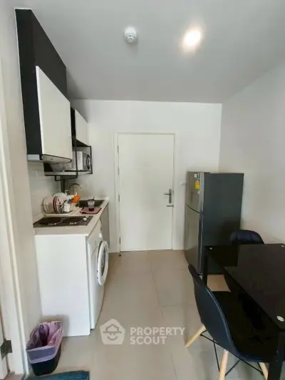 Modern compact kitchen with washing machine and dining area in a cozy apartment.